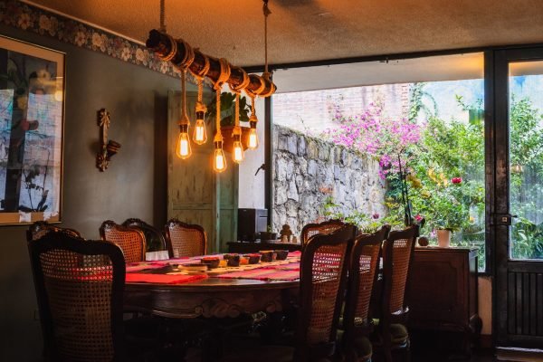 A rustic chandelier made of bulbs and ropes over a dining table in a vintage kitchen